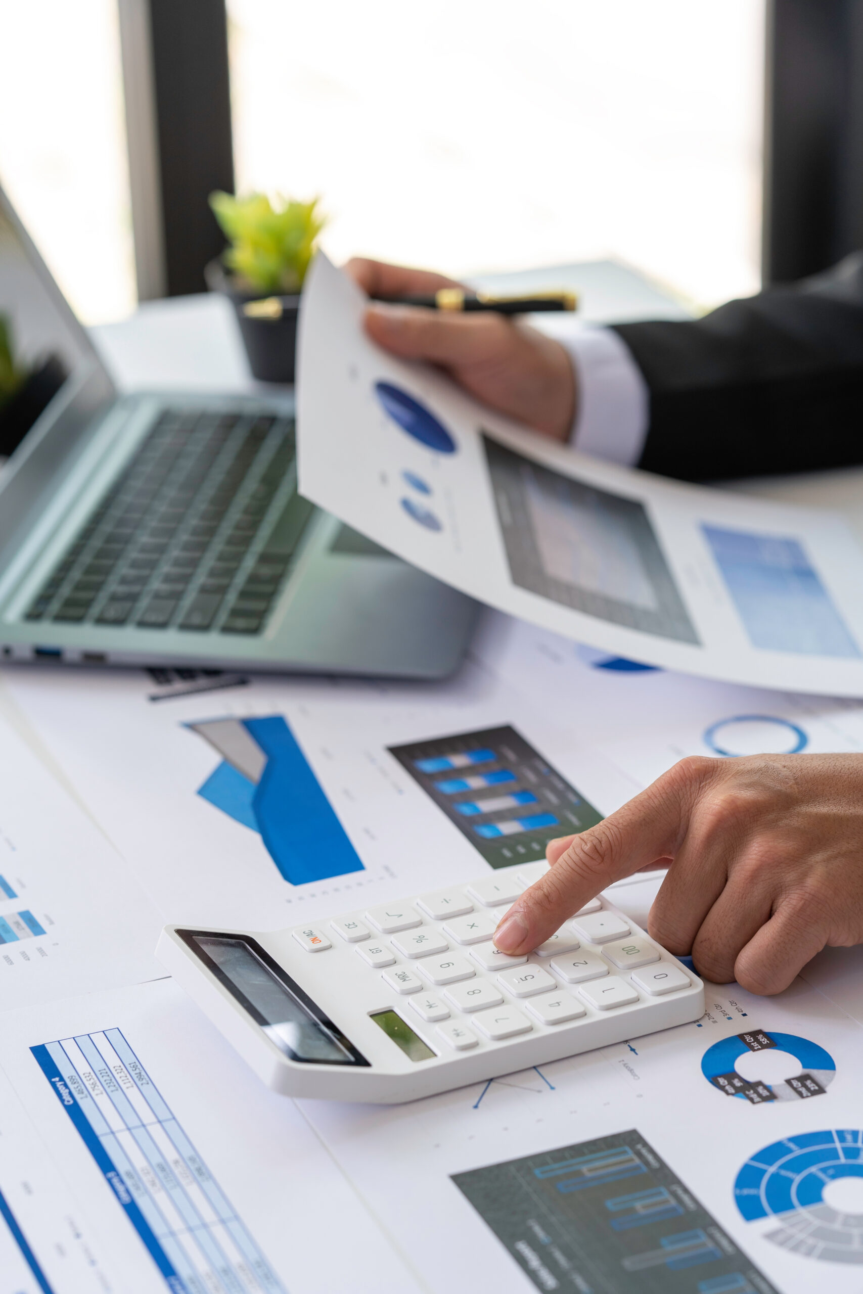 businessmen or accountants using a calculator calculates and laptop computer while working analytic business report on the workplace, Planning financial, accounting and investment concept.