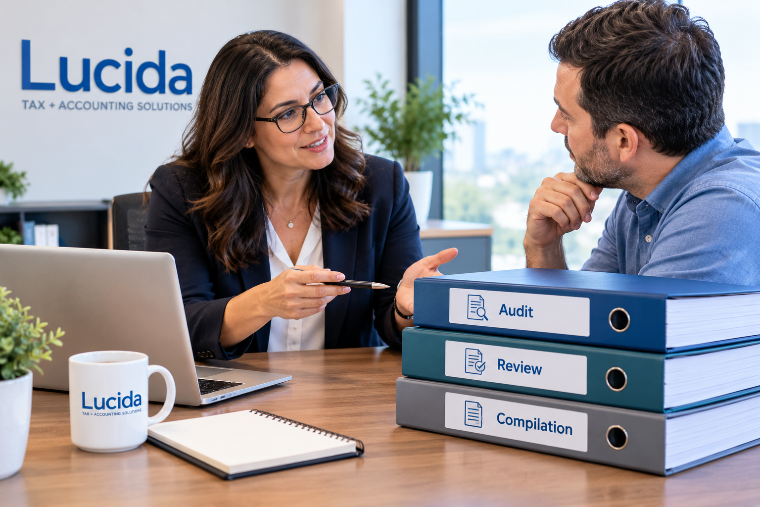 Lucida accountant explaining the difference between an audit, review, and compilation to a business owner, with three labeled binders on the desk